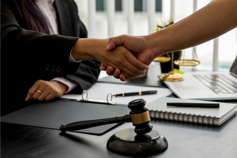 An image of a handshake between a lawyer and a client over an agreement of legal fees.